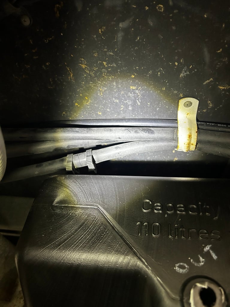 Close-up of a car engine component showing a connector, cable, and capacity marking text on dark metal surface