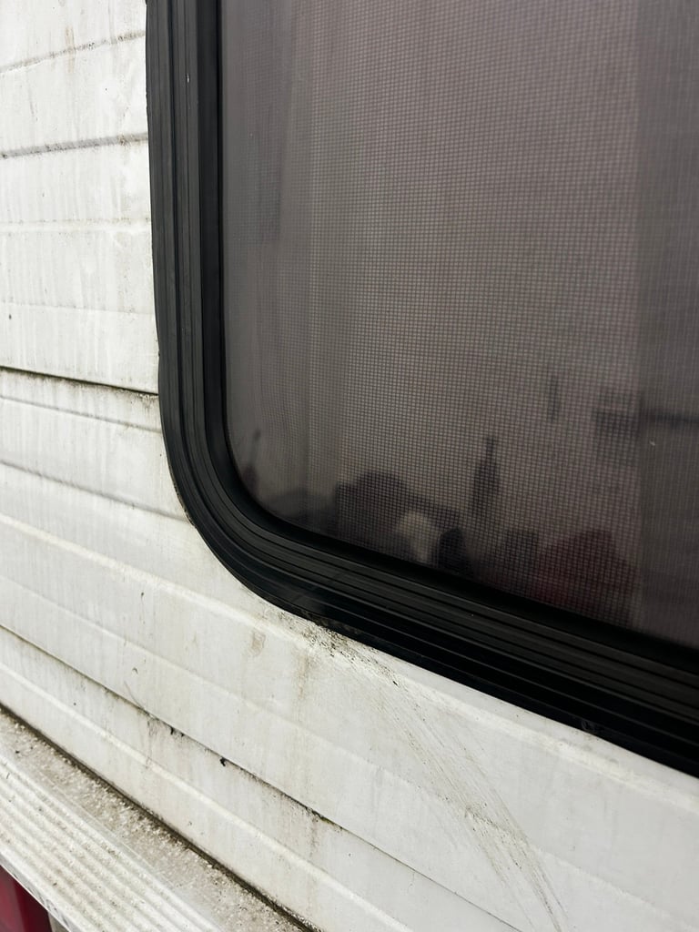 Close-up of a window screen with black frame attached to white exterior wall trim