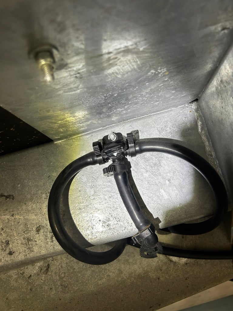 Black endoscope camera with flexible probe coiled on concrete surface next to metal equipment
