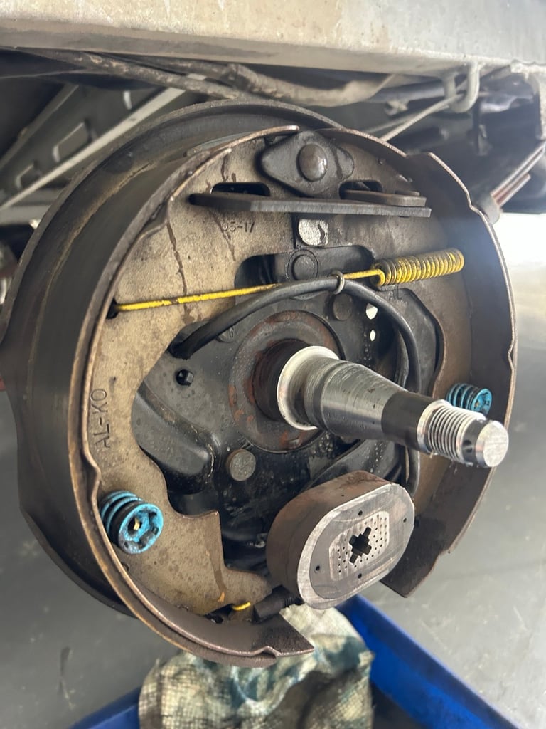 Disassembled car brake drum showing internal components including springs, adjuster wheel, and brake pads