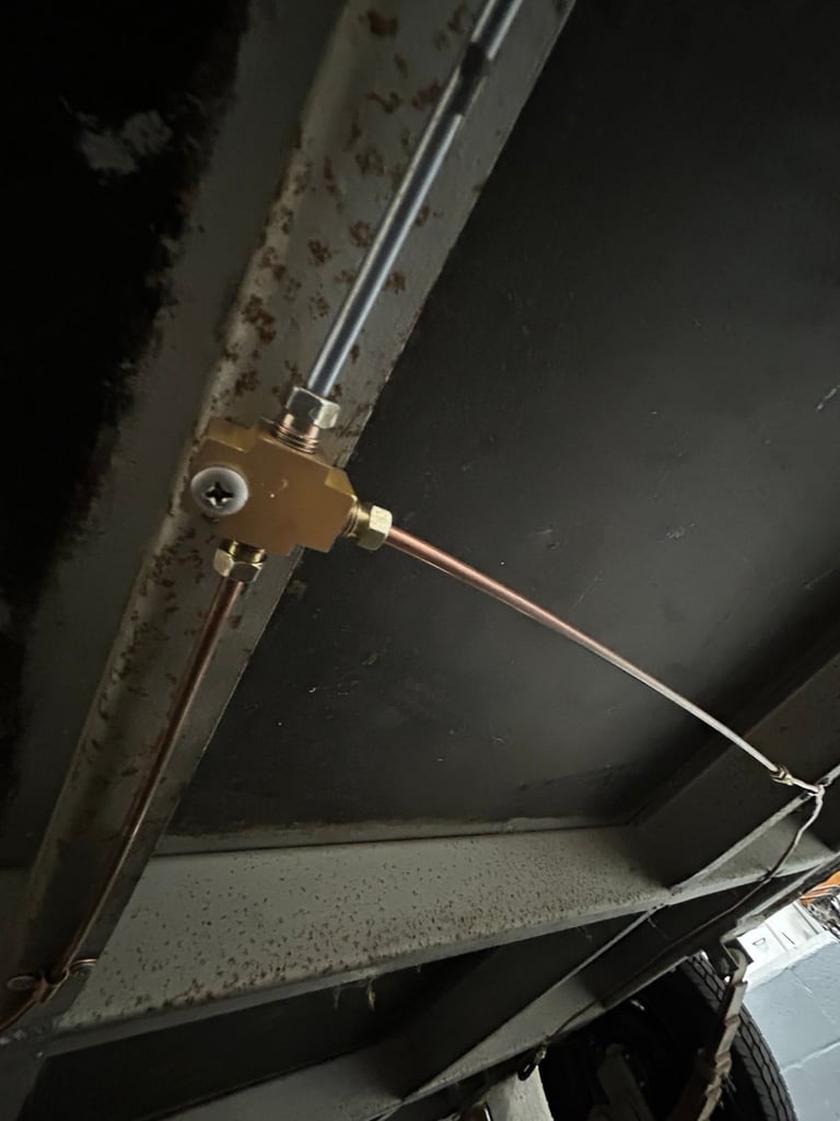 Close-up of a brass valve assembly mounted on a clear tube against a dark background, showing metal connectors and hardware details