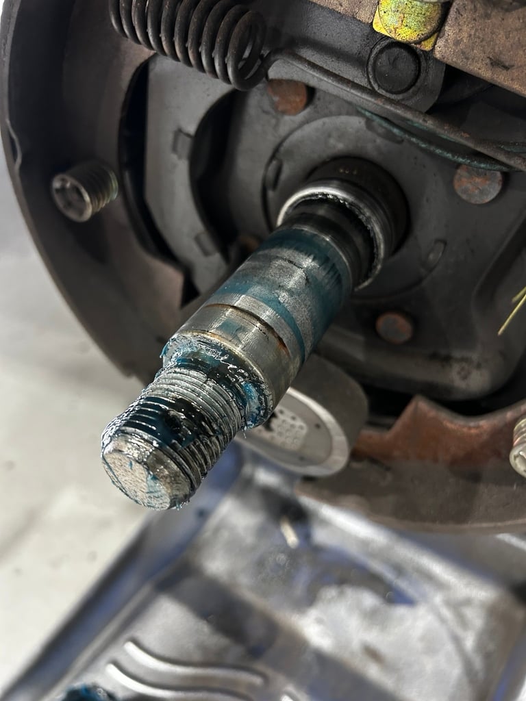 Close-up of a rusty metal bolt and screw assembly on vehicle brake components with visible corrosion