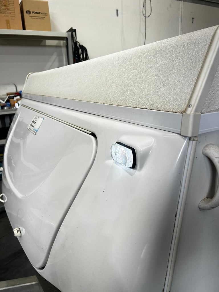 White front-load dryer with open door and textured cream-colored filter basket visible in an indoor utility space