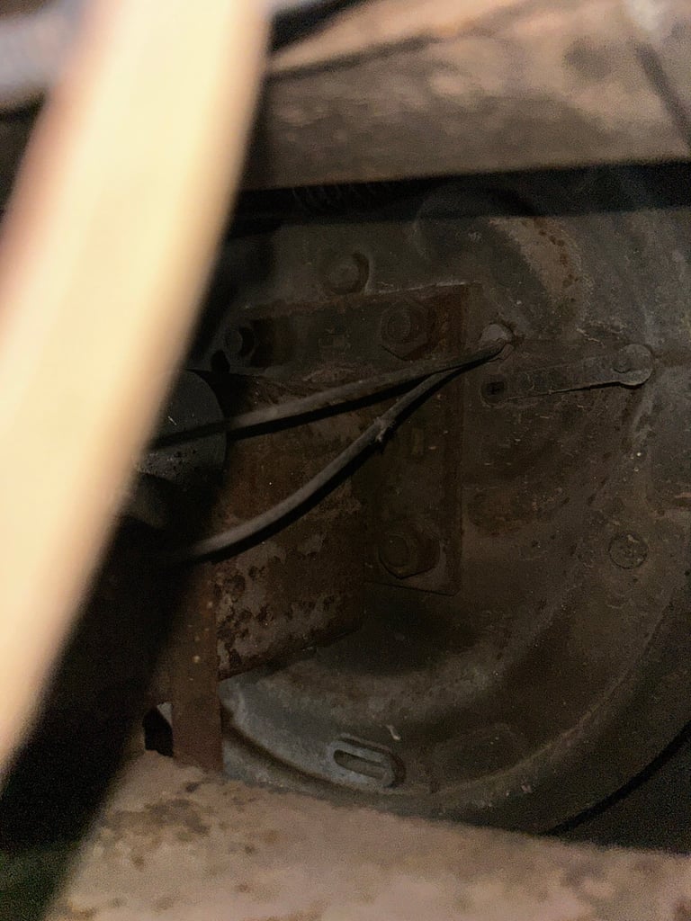 Close-up of a dusty electrical outlet or switch mounted on a dark wall with cables attached