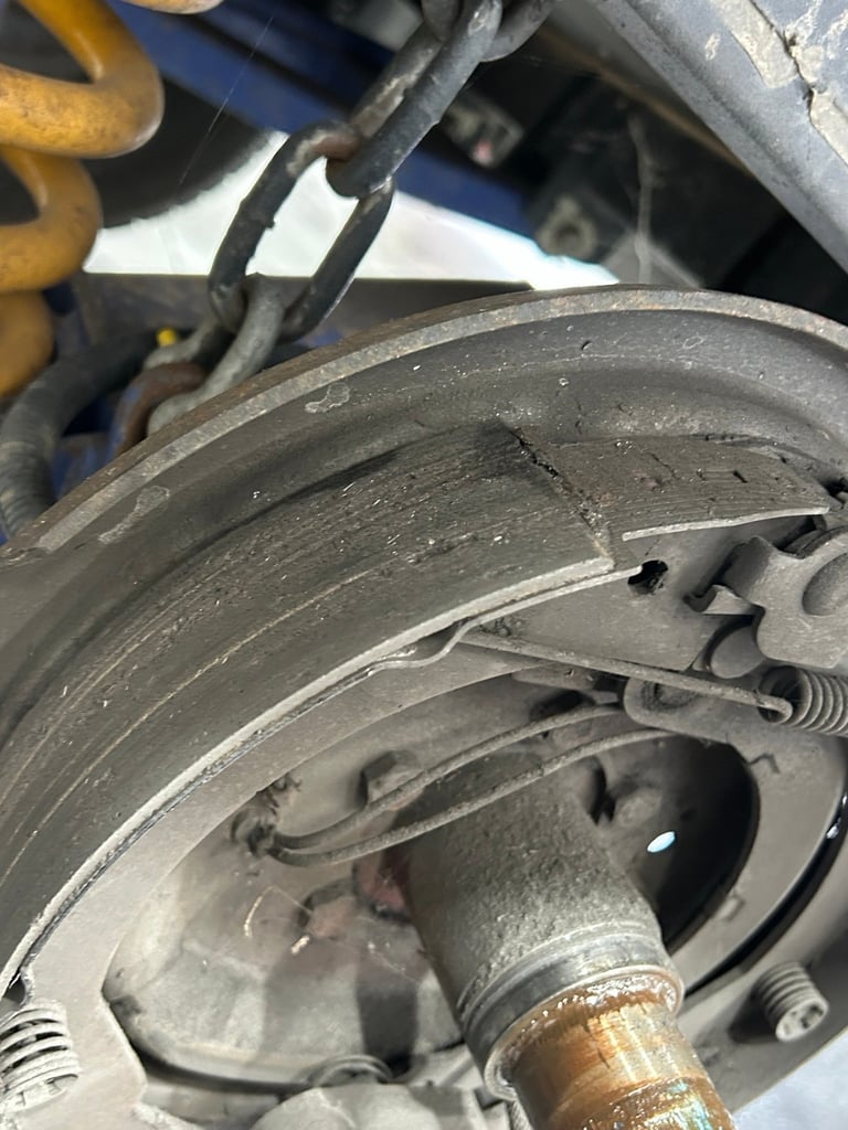 Close-up of a vehicles disc brake assembly showing the brake pad, rotor, and caliper with worn metal components