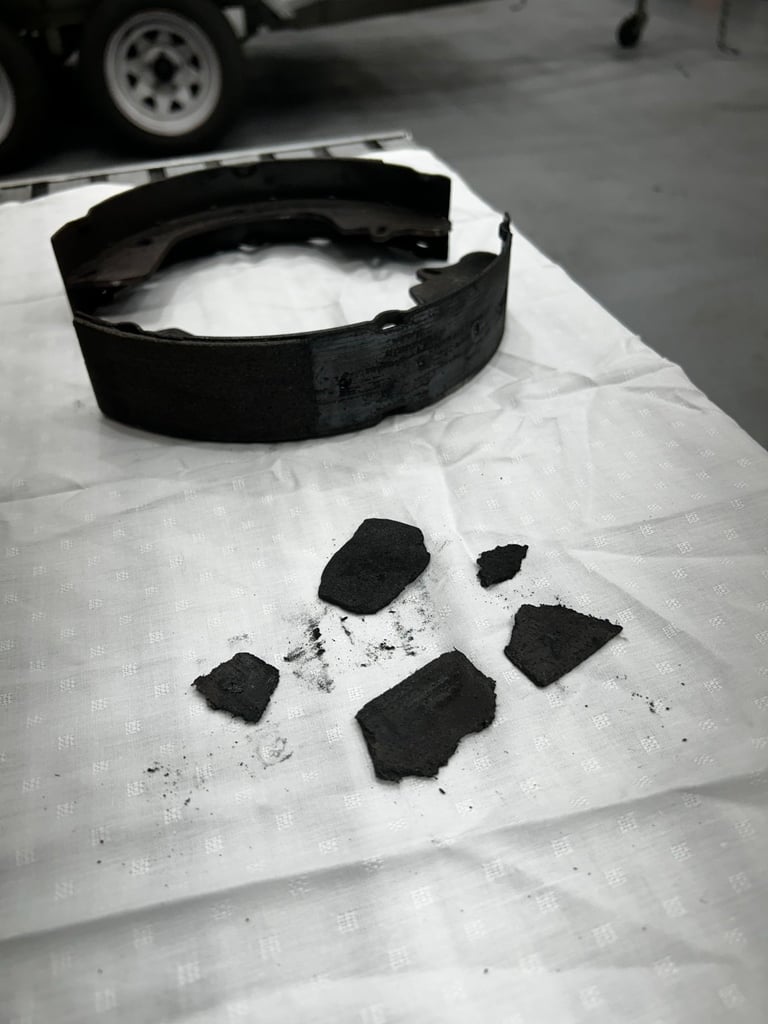 Black rubber seal or gasket with broken pieces on white paper sheet in garage setting