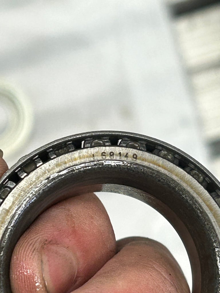 Close-up of a hand holding a metal ring with engraved numbers and text on the inner band