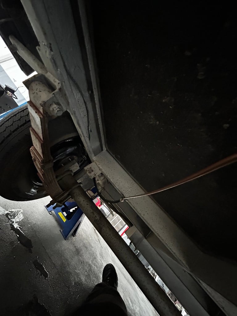 Overhead view of parked white car with open trunk door showing tool box and supplies inside garage