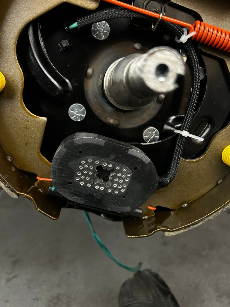Overhead view of disassembled ceiling light fixture showing motor mechanism, wiring, and components on gray surface