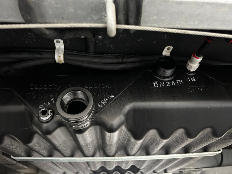 Close-up of car engine bay showing oil filler cap, hoses, and engine block with metal ribbed surface