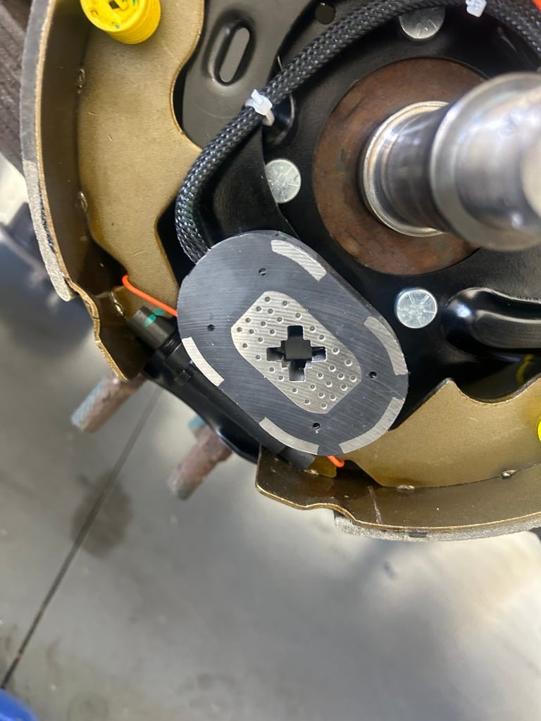 Close-up of internal mechanical assembly showing a metal footplate with crosshair markings, braided cables, and cylindrical components in a tan and black housing