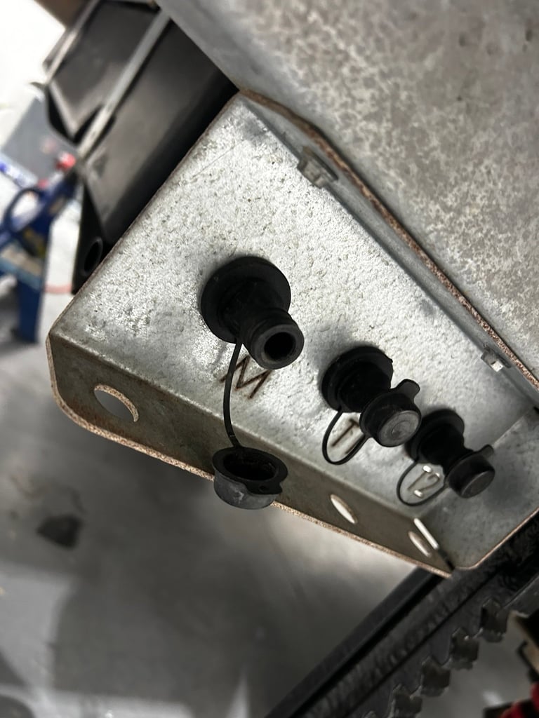 Close-up of metal junction box with multiple black rubber cable glands and wiring connections